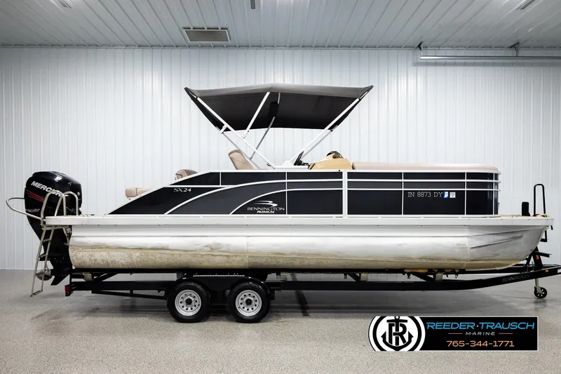 Slide: The Image of 2018 Bennington 24 SSBXPDL pontoon boat with canopy, displayed indoors on a trailer. - 5