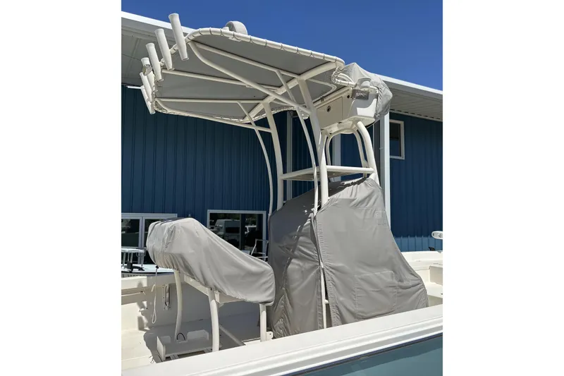 Slide: The Image of 2014 Pathfinder 2600 HPS boat with covered seating and T-top against blue building. - 13