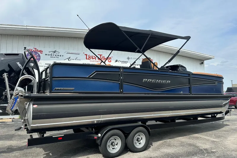 Slide: The Image of 2026 Premier 250 Intrigue RLO pontoon boat on trailer, blue and black design. - 2