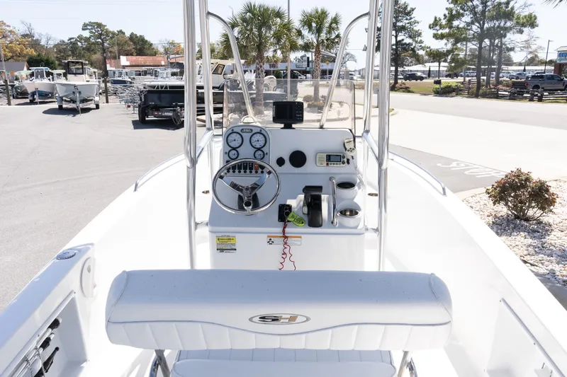 Slide: The Image of 2012 Sea Hunt Triton 188 boat dashboard with steering wheel and controls, parked outdoors. - 10