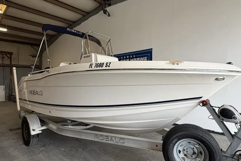 Slide: The Image of 2018 Robalo R180 Center Console boat on trailer in garage setting. - 1