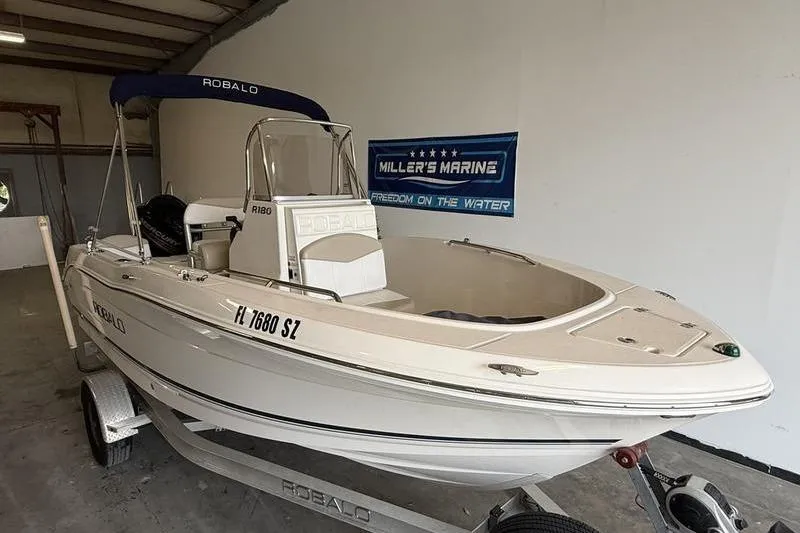 Slide: The Image of 2018 Robalo R180 Center Console boat on trailer in showroom. - 2