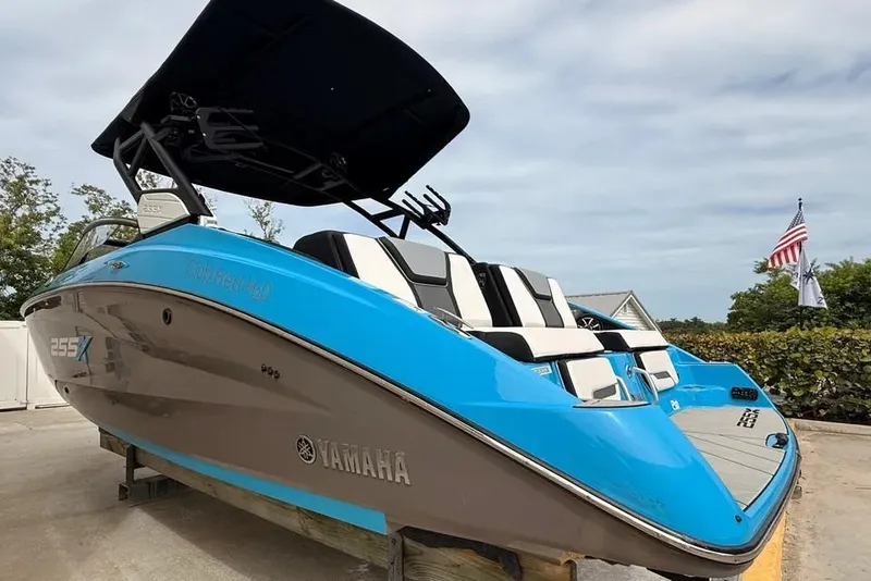 Slide: The Image of 2022 Yamaha Boats 255XD in vibrant blue, docked outdoors under a cloudy sky. - 1