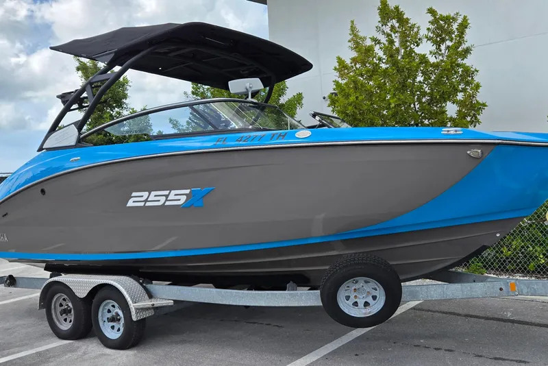 Slide: The Image of 2022 Yamaha Boats 255XD on trailer, blue and gray design, parked outdoors. - 13