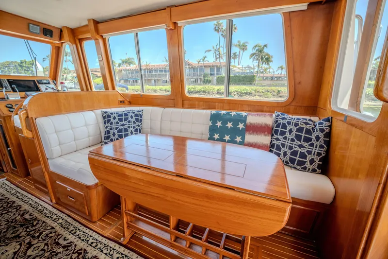 Slide: The Image of Interior of 1998 Grand Banks 43 Eastbay EX with wooden table and nautical-themed cushions. - 12