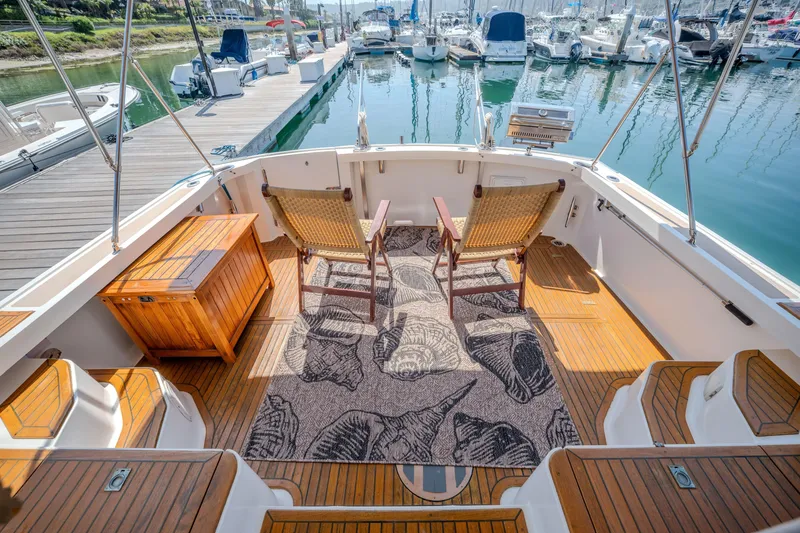 Slide: The Image of 1998 Grand Banks 43 Eastbay EX yacht deck with chairs, wooden flooring, and marina view. - 9