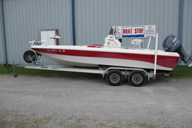 The Image of 2005 NauticStar 2200 NauticBay boat on trailer, parked beside a building. - 0