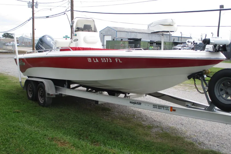 Slide: The Image of 2005 NauticStar 2200 NauticBay boat on trailer, red and white design, parked on grass. - 1