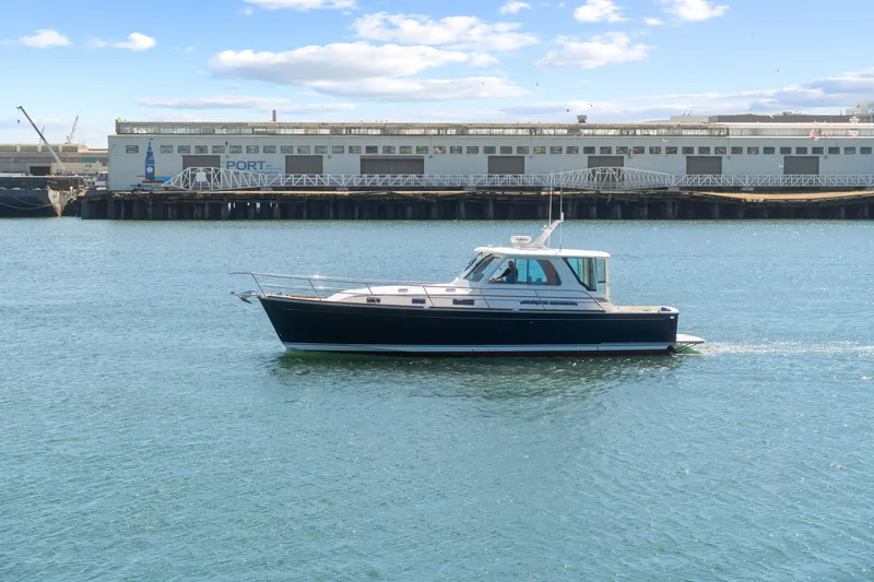 Slide: The Image of 2007 Sabre 42 Hard Top Express yacht cruising near a port building under a blue sky. - 10