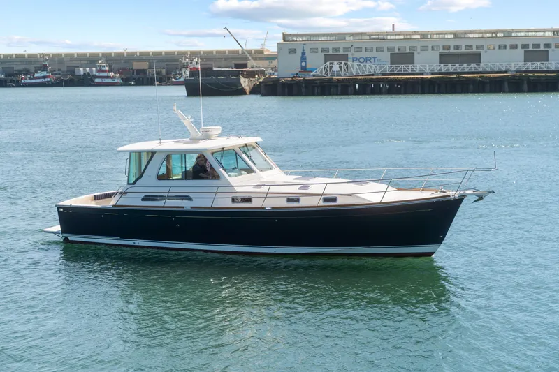 Slide: The Image of 2007 Sabre 42 Hard Top Express yacht cruising in a harbor with industrial backdrop. - 12