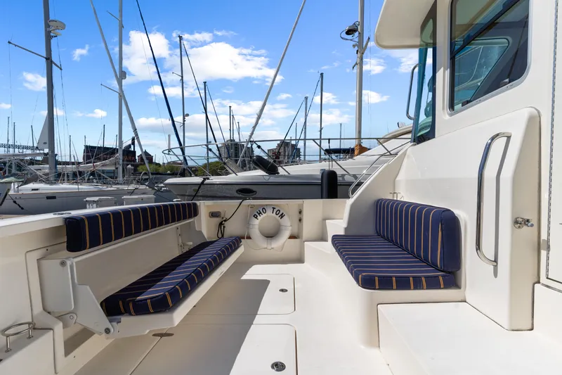 Slide: The Image of 2007 Sabre 42 Hard Top Express yacht deck with striped seating and marina view. - 4