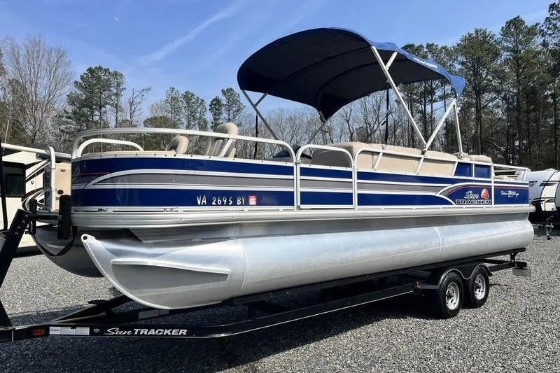 The Image of 2015 Sun Tracker Fishin' Barge 24 DLX pontoon boat on trailer, parked outdoors. - 1