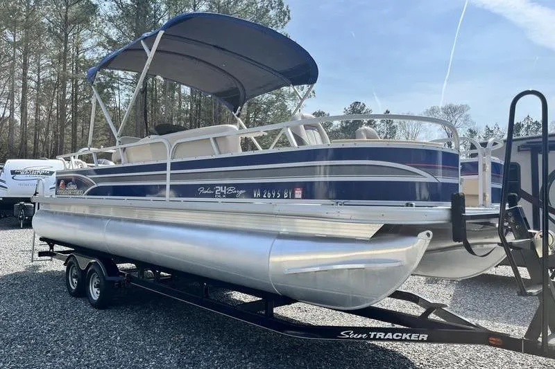 Slide: The Image of 2015 Sun Tracker Fishin' Barge 24 DLX pontoon boat on trailer, parked outdoors. - 4