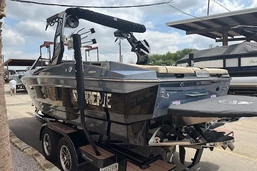 Slide: The Image of 2024 Supreme S220 boat on trailer, sleek design, parked outdoors under cloudy sky. - 6