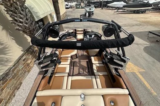 Slide: The Image of 2024 Supreme S220 boat interior with tan and brown seating, docked outdoors. - 8