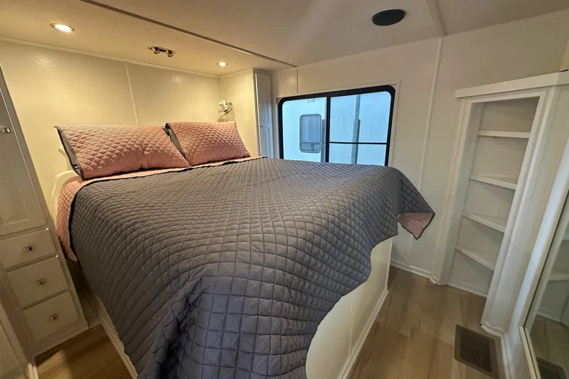 Slide: The Image of Cozy bedroom in 1998 Stardust Cruisers 16x84 houseboat with quilted bedding and built-in shelves. - 7