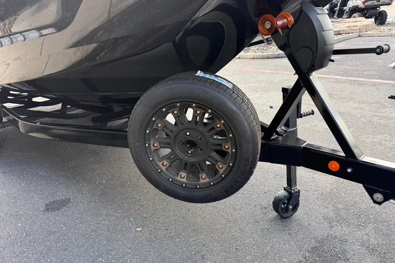 Slide: The Image of Trailer wheel of a 2024 MasterCraft X24 boat on pavement. - 10