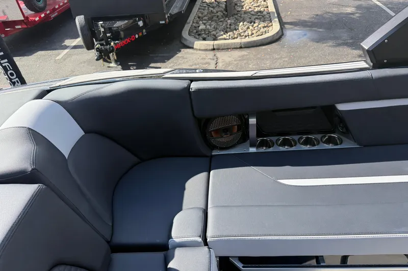 Slide: The Image of 2024 MasterCraft X24 boat interior with gray seating, cup holders, and speaker. - 19