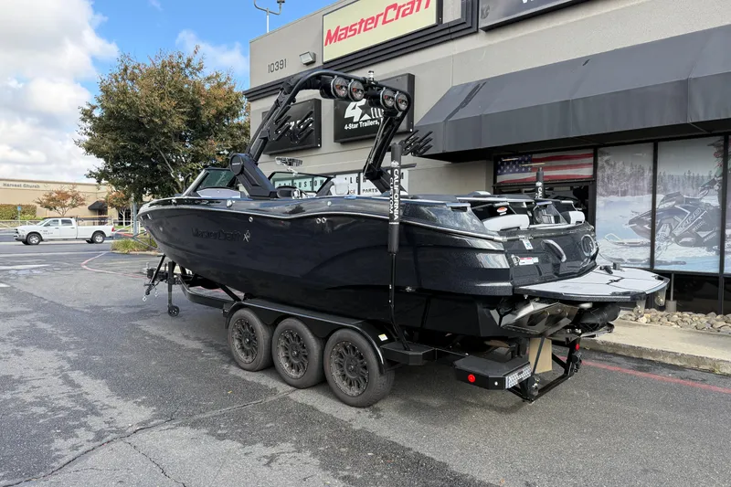 Slide: The Image of 2024 MasterCraft X24 boat on trailer outside dealership, showcasing sleek design and modern features. - 2