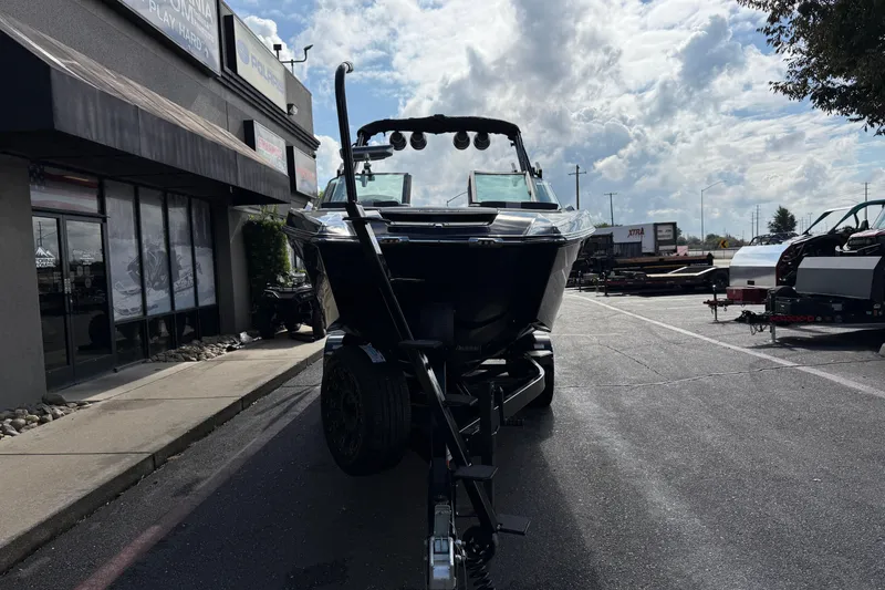 Slide: The Image of 2024 MasterCraft X24 boat on trailer outside dealership under cloudy sky. - 6