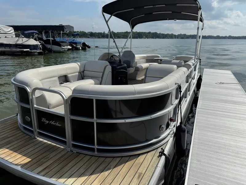 Slide: The Image of 2000 Sanpan 25 pontoon boat docked, calm lake background. - 2