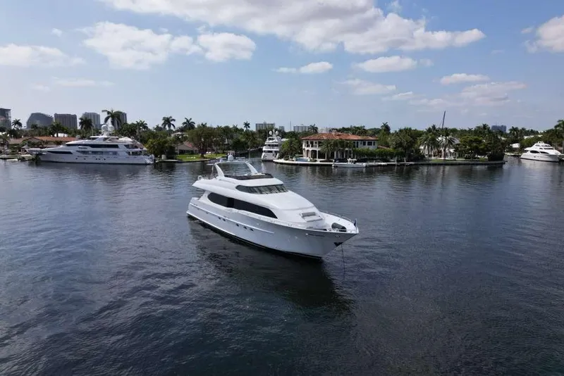 Slide: The Image of 2001 Lazzara Motoryacht cruising on a serene waterway with luxury homes and yachts. - 10