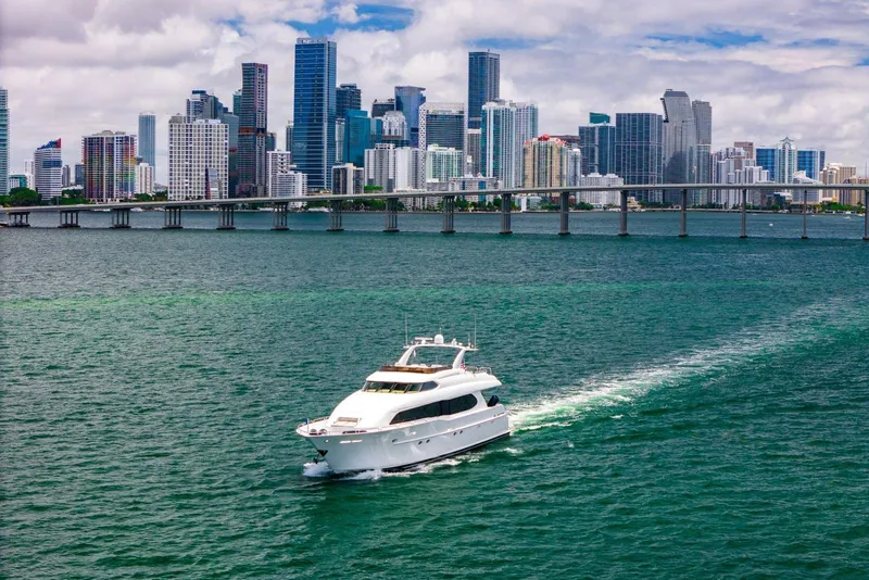 Slide: The Image of 2001 Lazzara Motoryacht cruising near a city skyline with a bridge in the background. - 2