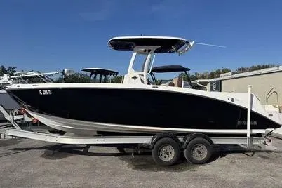 Slide: The Image of 2021 Yamaha Boats 255 FSH Sport E on trailer, sleek black design, outdoor setting. - 10