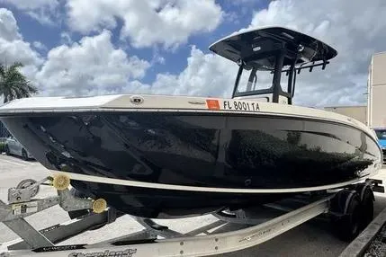 Slide: The Image of 2021 Yamaha Boats 255 FSH Sport E on trailer, sleek black design, parked outdoors. - 5