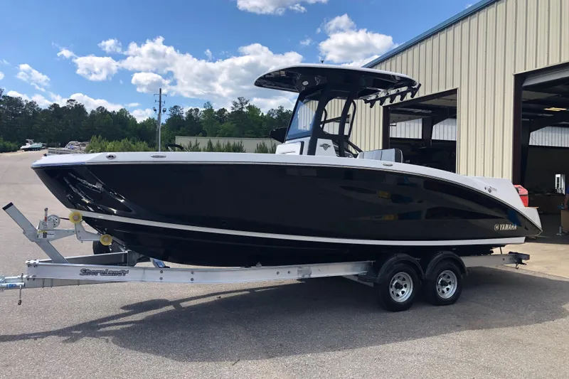 Slide: The Image of 2021 Yamaha Boats 255 FSH Sport E on trailer, parked outside a warehouse. - 8