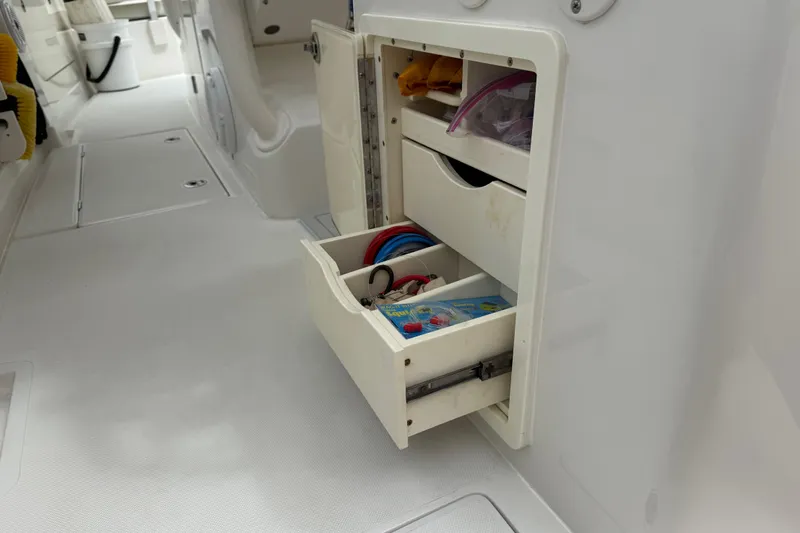 Slide: The Image of Open storage compartment on 2012 Jupiter 34 FS boat, showing organized drawers and equipment. - 16