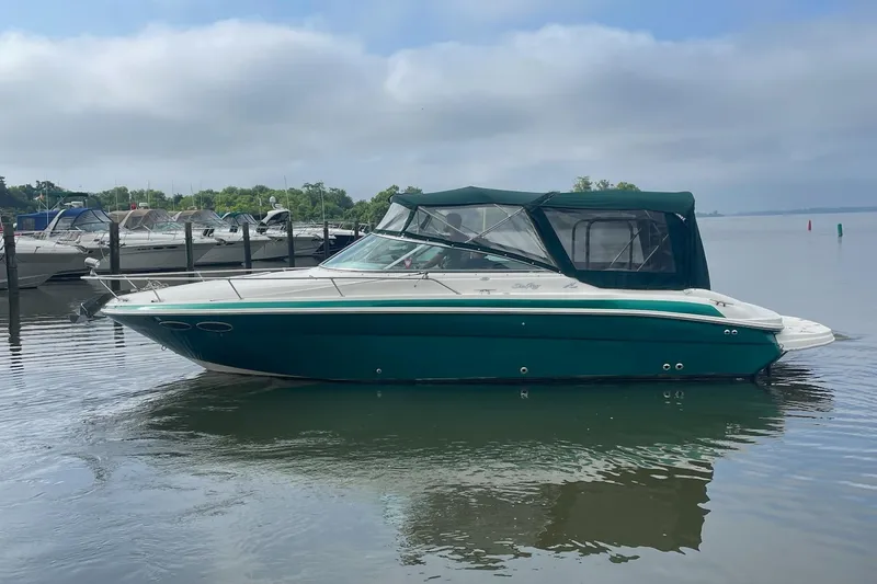 Slide: The Image of 2001 Sea Ray 280 Sun Sport boat docked on calm water under cloudy sky. - 2