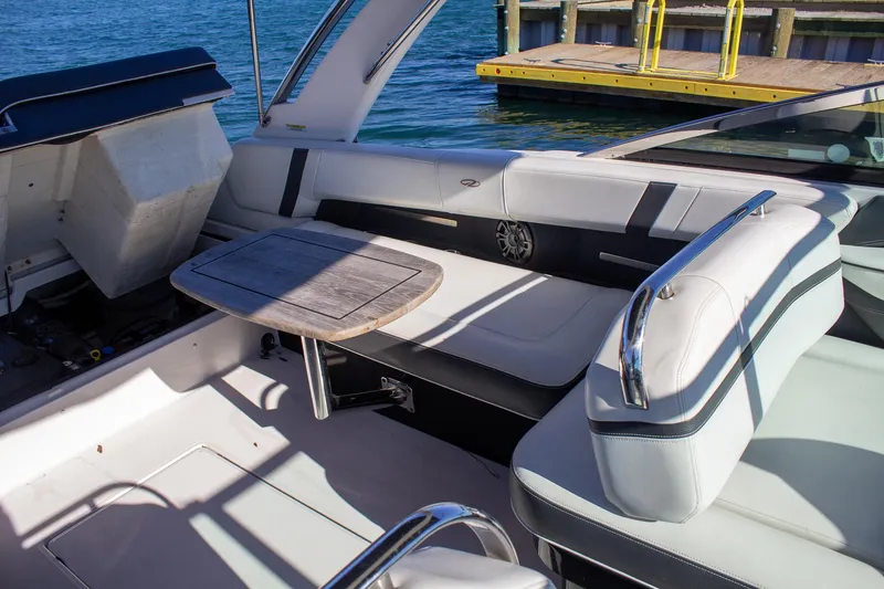 Slide: The Image of 2015 Regal 2800 boat interior with seating and table, docked by the water. - 21