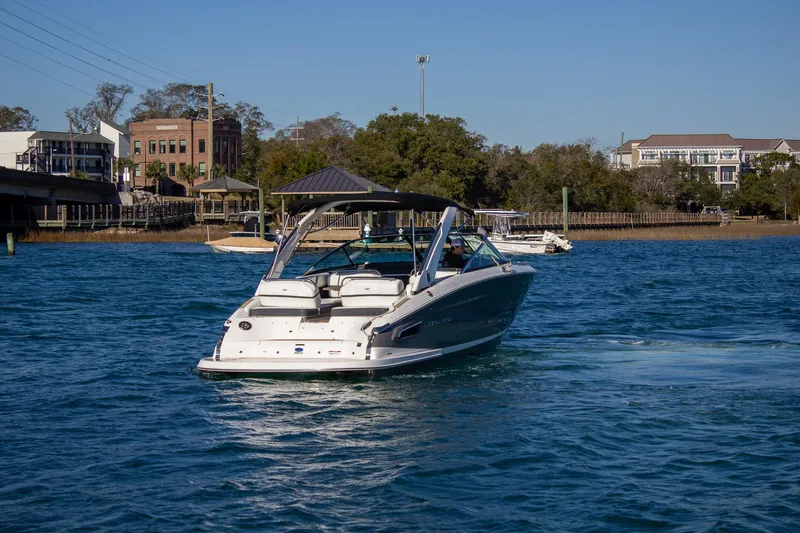 Slide: The Image of 2015 Regal 2800 boat cruising on a sunny day in a scenic waterfront area. - 5