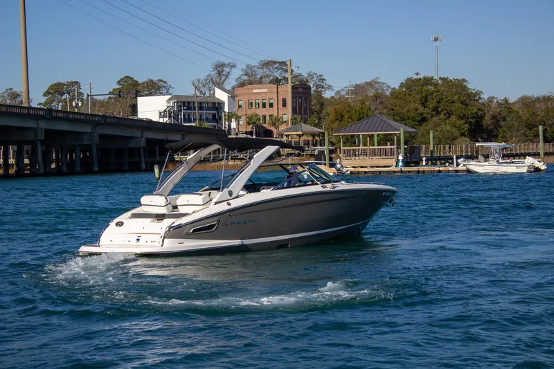 Slide: The Image of 2015 Regal 2800 boat cruising on a sunny day near a bridge and waterfront buildings. - 6