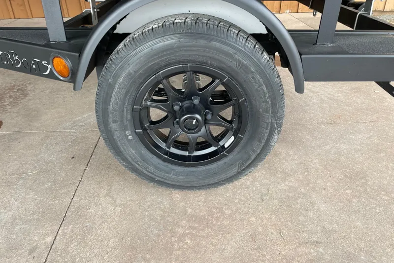 Slide: The Image of Black wheel of 2026 Reaper Boats 653 Timber Reaper trailer on concrete surface. - 14