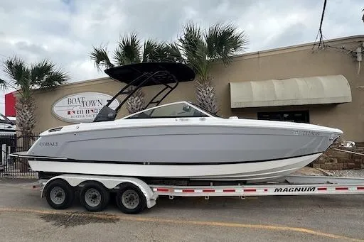 The Image of 2024 Cobalt R8 boat on trailer, parked outside a building with palm trees. - 0