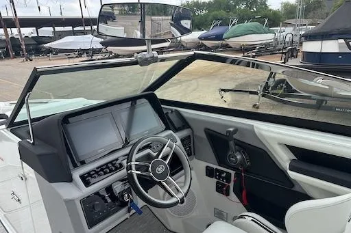 Slide: The Image of 2024 Cobalt R8 boat dashboard with steering wheel and control panel, docked near other boats. - 16