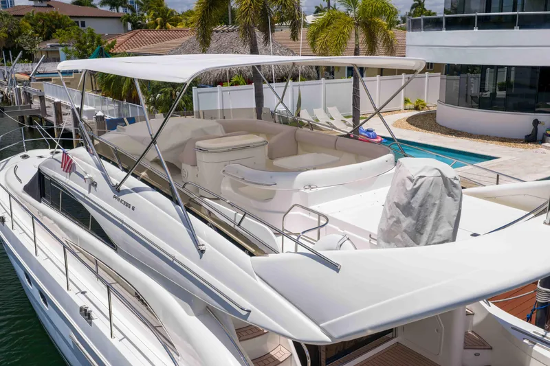 Slide: The Image of 2002 Princess 61 yacht docked by a poolside, featuring spacious deck and seating area. - 5