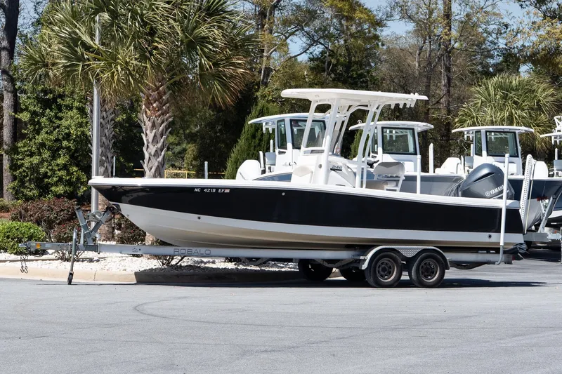 The Image of 2017 Robalo 246 Cayman boat on trailer, parked near palm trees. - 1