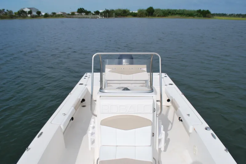 Slide: The Image of 2016 Robalo 226 Cayman boat on calm water, showcasing spacious deck and seating. - 5
