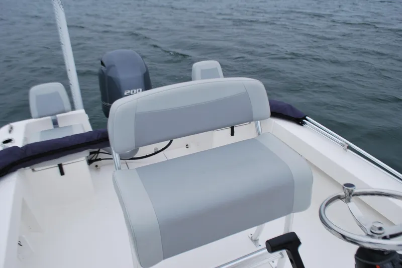 Slide: The Image of 2023 Bay Rider 239 Bay boat interior with seating and steering wheel on water. - 16