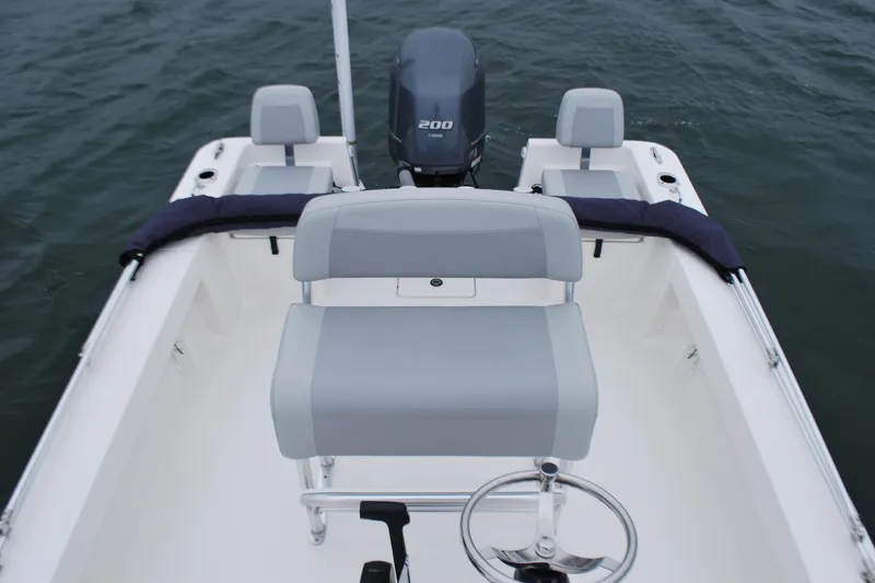 Slide: The Image of 2023 Bay Rider 239 Bay boat interior with seating and steering wheel on water. - 18