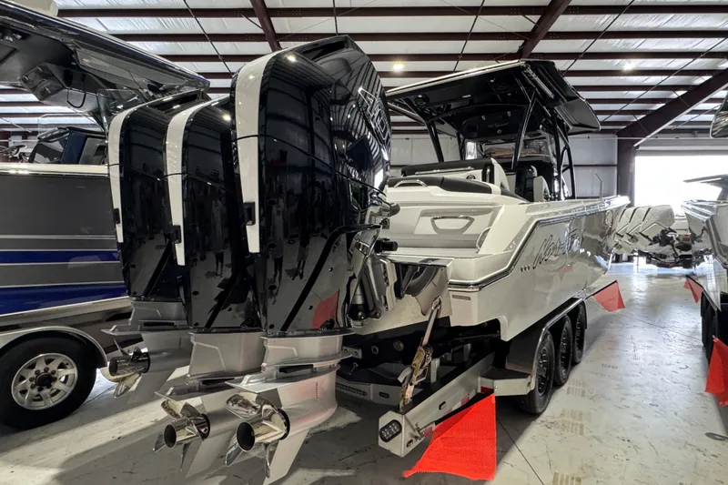 Slide: The Image of 2026 Nor-Tech 390 Sport Center Console boat with powerful outboard engines in a showroom. - 11