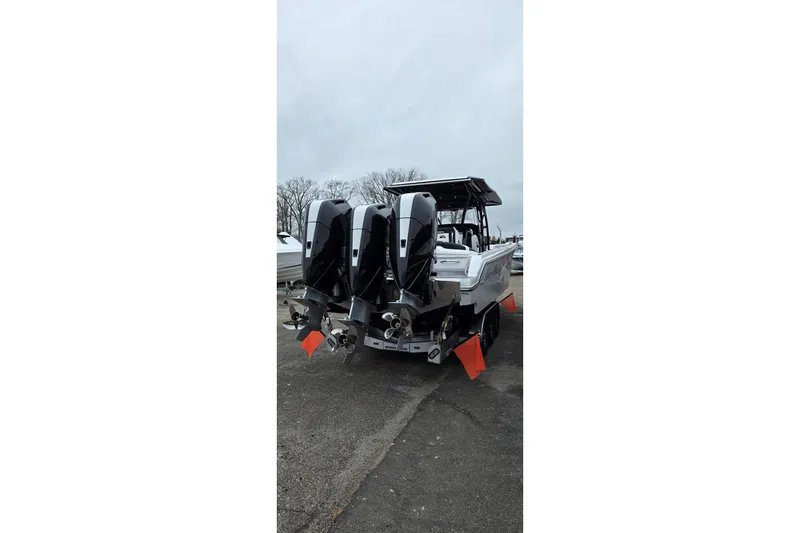 Slide: The Image of 2026 Nor-Tech 390 Sport Center Console with triple outboard engines, docked on a cloudy day. - 21