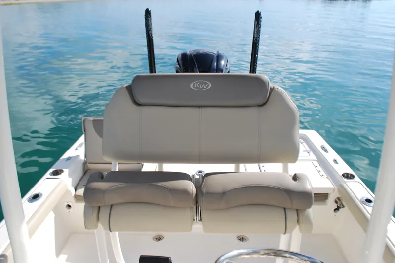 Slide: The Image of 2021 Key West 210 Bay Reef boat interior with cushioned seating and calm water backdrop. - 13