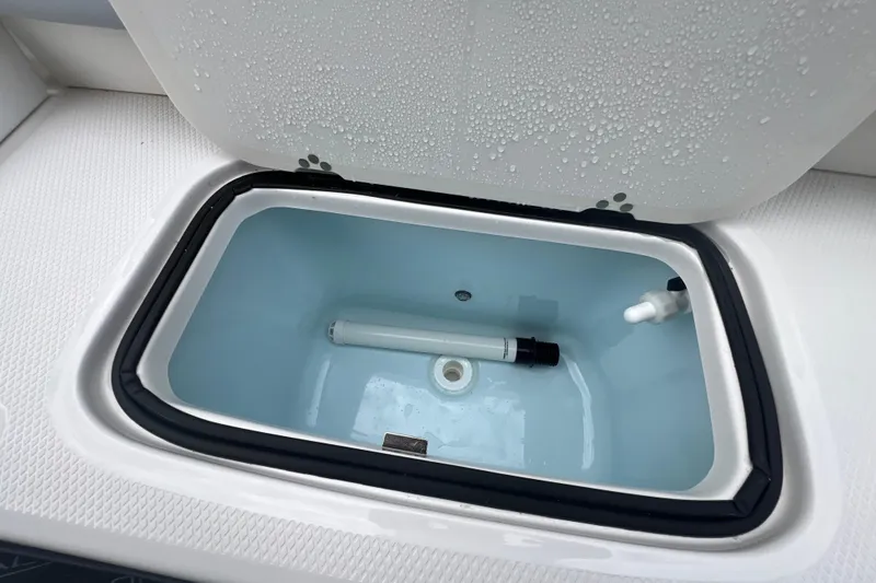 Slide: The Image of Livewell compartment on 2026 Robalo R207 Dual Console boat, open with water droplets. - 13