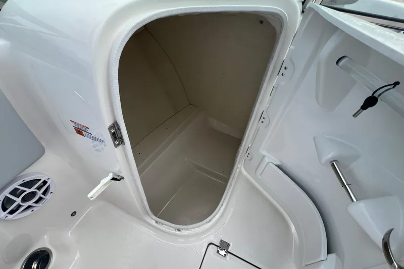 Slide: The Image of 2026 Robalo R207 Dual Console storage compartment, open door, white interior. - 16