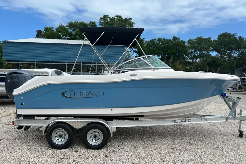 Slide: The Image of 2026 Robalo R207 Dual Console boat on trailer, blue and white design, outdoor setting. - 5