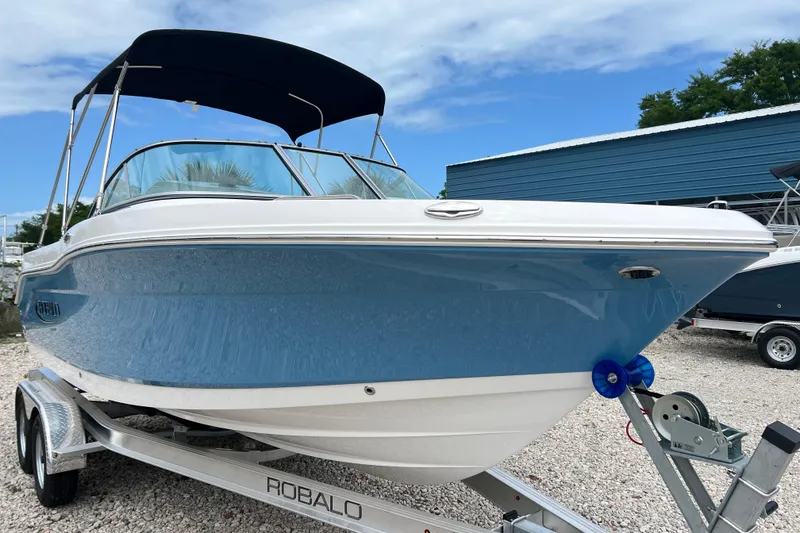 Slide: The Image of 2026 Robalo R207 Dual Console boat on trailer, blue hull, under clear sky. - 6